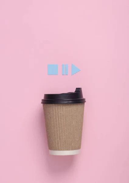 Coffee cup with icons start, stop, pause of media player on pink background. Top view