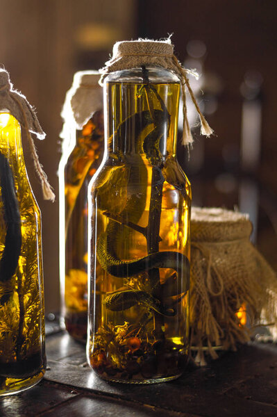 Alcoholic drink, tincture using a snake. Alcoholic drink infused with snake venom. Homemade alcohol with the addition of snake and herbs. A potion with medicinal herbs and a snake.