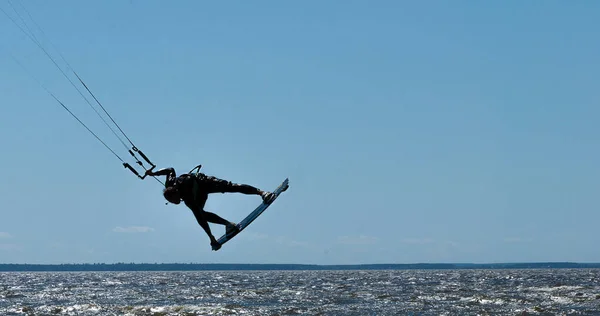 Bir adam uçurtma sürüyor, bir paraşütle denizde.