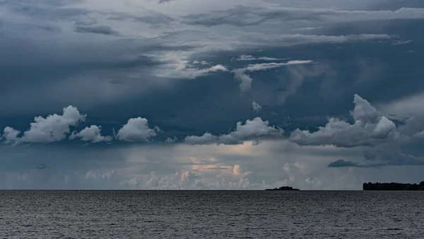 Denizin üzerindeki karanlık gökyüzü, arka plandaki beyaz bulutlar..