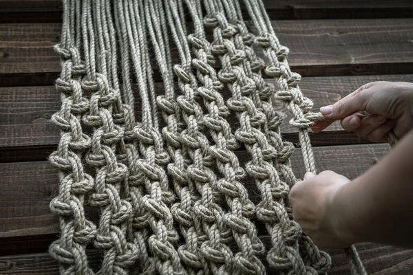 Bir kız büyük düğümlü dekoratif bir halı örüyor.