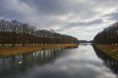 Güvertede bir göl manzarası Sudaki ağaçların yansımalarıyla, bulutlu gökyüzü, sonbahar
