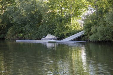 Özel iskele ve bir tekne, yeşil yapraklar.