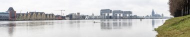 Köln panoraması, karlı havada vinç evleri ve Köln katedrali. Ren nehri yüksek suyla