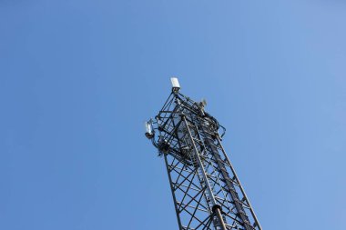 Arkaplanı mavi gökyüzü olan telekomünikasyon anteni