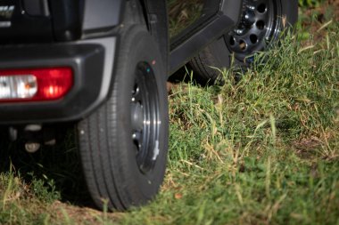 Küçük siyah bir off-road aracının yakınında. Bir çayırda duruyor.