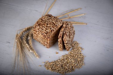 Gri bir tahtanın üzerinde buğday, çavdar ve ayçekirdeği ile kepekli ekmek.