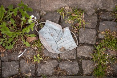 Atılmış ya da kaybolmuş yüz maskeleri, bokeh arka plandaki insanlar, yağmurlu günler.