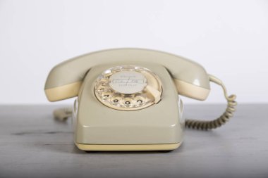 Tahta tahtada çevirmeli eski gri telefon, beyaz arka plan.