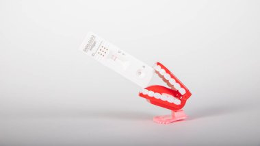 Dişlerinin arasında negatif korona antijen testi olan oyuncak ağız, beyaz arka plan.