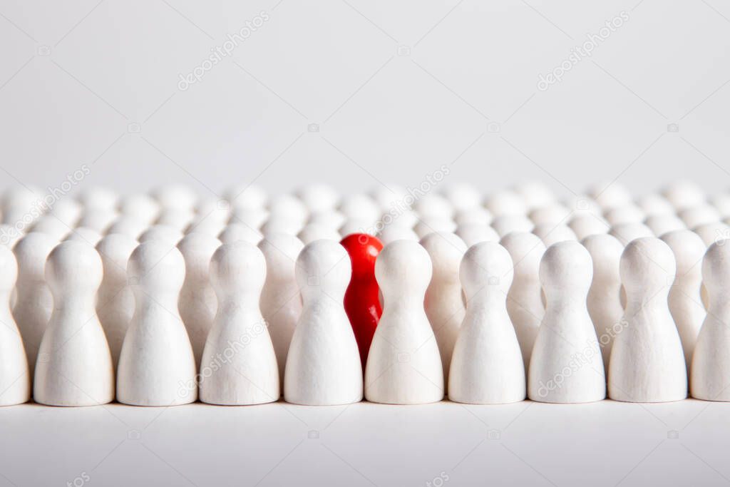 many white wooden figurines and one red