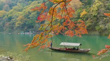 KYOTO, JAPONYA - 15 Kasım 2018: kayıkçı nehirde tekneye biniyor. Sonbahar mevsiminde Arashiyama, Kyoto, Japonya