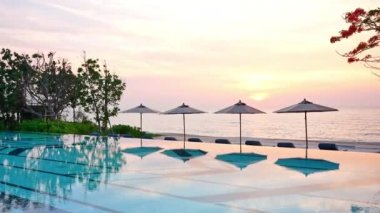 Güneş şemsiyeleri ve gün batımında deniz ve havuz manzarası 