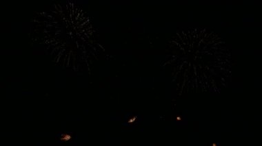 Karanlık gece gökyüzünde parlayan renkli havai fişeklerin 4K videosu