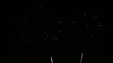 Karanlık gece gökyüzünde parlayan renkli havai fişeklerin 4K videosu