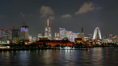 Panoramic night cityscape, illuminated buildings, observation circle reflected in sea