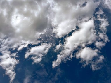 Beyaz tüylü kümülüs ve parlak mavi bahar gökyüzünde sirrus bulutları. Bulutlu bahar havası. Seçici odak.