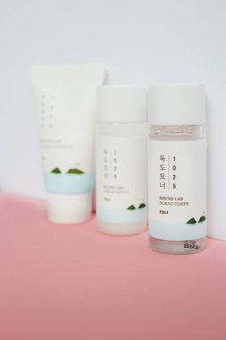 KYIV, UKRAINE - 19 AUGUST 2022: Set of three korean skin care products Round Lab tonic, lotion and cleanser in travel size packaging on white and pink background. Selective focus.