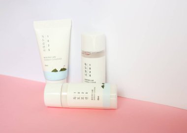 KYIV, UKRAINE - 19 AUGUST 2022: Korean cosmetics brand Round Lab set of mini products cleanser, lotion and tonic. Flat lay with white and pink colors. Selective focus.