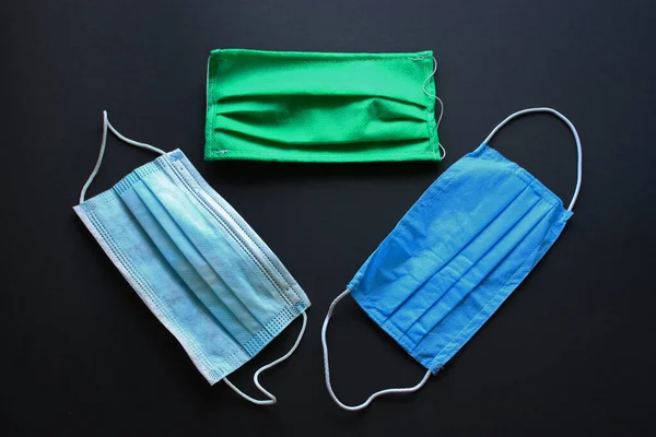Three colorful cotton surgical mask composition on a black background. Protection against bacterias and viruses. World pandemic.