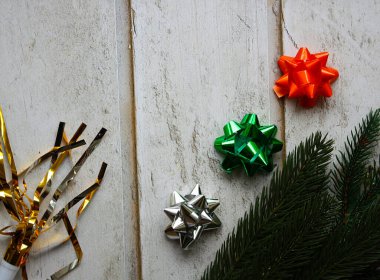 Köknar ağacı dalları, pırıl pırıl yeşil, turuncu, gümüş hediye yayları ve ahşap arka planda altın süslemeleri olan şenlikli bir kompozisyon. Üst Manzara. Düz yatıyordu. Noel arkaplanı.