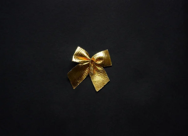黑色背景上的一个金色闪光的礼物弓 顶部视图 — 图库照片