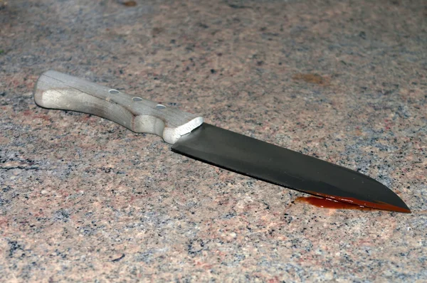 Symbolic image: knife with wooden handle and blood on the cutting edge