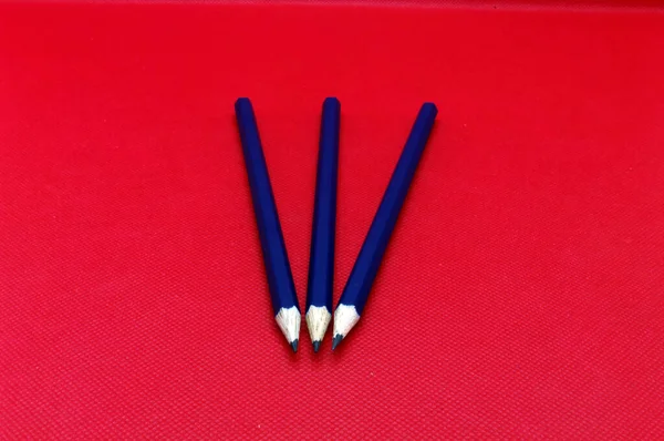 Writing utensils: Three pencils on red background