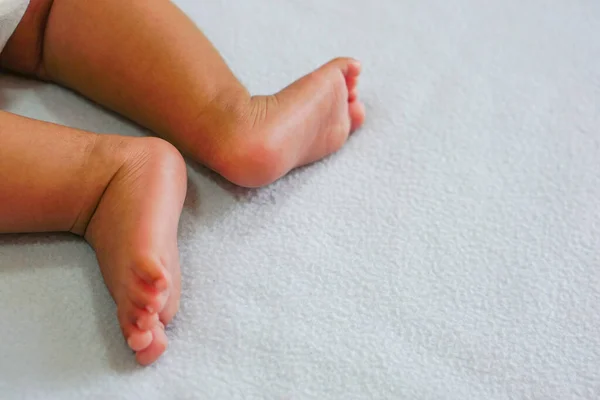 The feet of a newborn baby on a blue cloth.