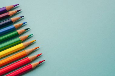 Mavi arkaplanda renkli kalemlerin ya da pastelin üst görüntüsü. Öğrenme, öğrenme ve sunum kavramı.