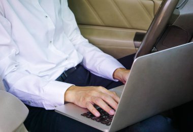 Businessman working on laptop while sitting on driver seat in  car. Lifestyle concept.