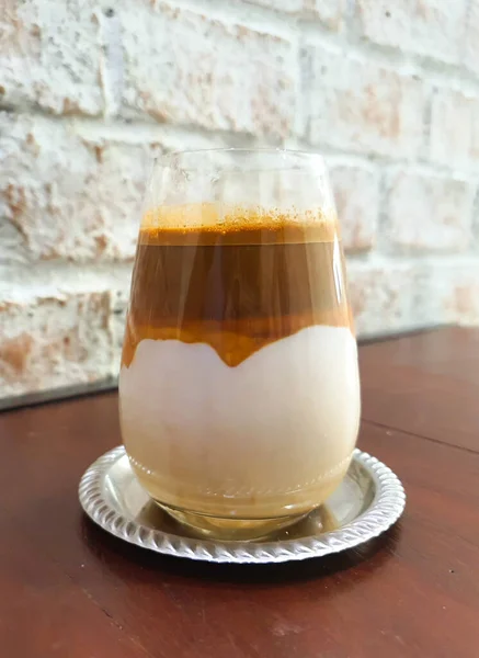 Kirli Kahve - Bir bardak espresso ve soğuk taze sütle karıştırılmış ahşap masaya konmuş kahve dükkanı ve restoranda beyaz tuğla duvar arkasında