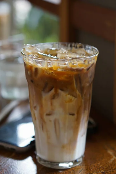 Bir bardak soğuk buzlu kahve eski ahşap masa arkaplanının üzerine.