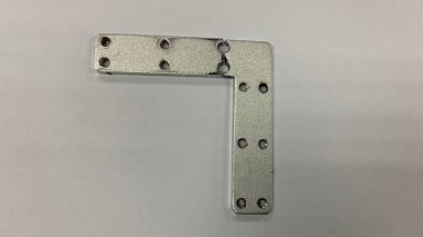 Gümüş renkli L plaka parçacığı hasarlı.