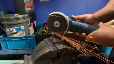 Metali keskin kıvılcımlarla kesen endüstriyel işçiler. Erkek, atölyede metal kesmek için özel bir alet kullanıyor. Metal işlemeden yükselen kıvılcımlar. Malezya, 14 Nisan 2022