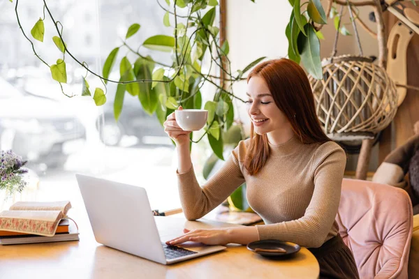 Mulher Sorridente Com Cabelo Vermelho Segurando Xícara Café Usando Laptop — Fotografia de Stock