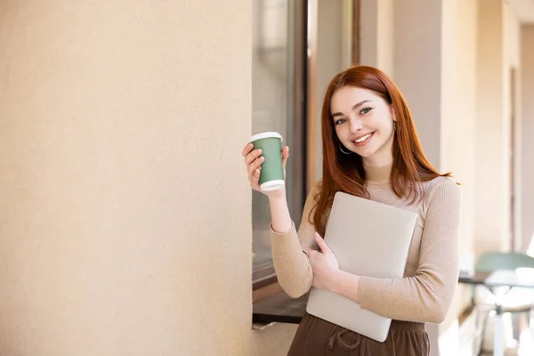 Щаслива Молода Жінка Рудим Волоссям Тримає Ноутбук Паперовий Стакан Біля — стокове фото