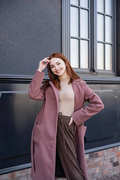 Cheerful Redhead Woman Stylish Coat Standing Hand Hip Modern Building — Stock Photo, Image