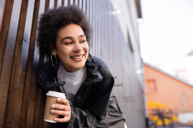 Neşeli Afro-Amerikan kadınının düşük açılı görüntüsü. Elinde yiyecek içecek ve saman bıyıklı bir kadın.