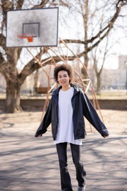 Basketbol sahasında ceketli mutlu Afrikalı Amerikalı kadın.