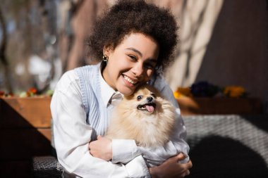 Mutlu Afro-Amerikan kadını Pomeranian Spitz sarılıyor 