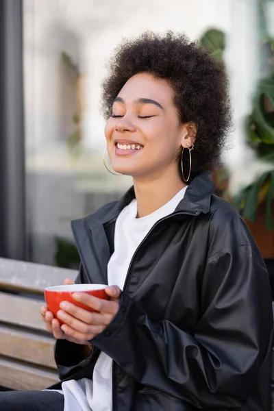 Усміхнена Афроамериканська Жінка Закритими Очима Тримає Чашку Кави Вулиці — стокове фото