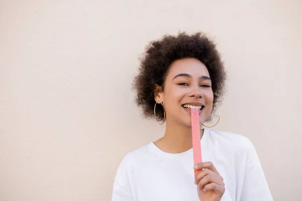Smiling African American Young Woman Eating Sweet Jelly Bubble Tape — Foto Stock