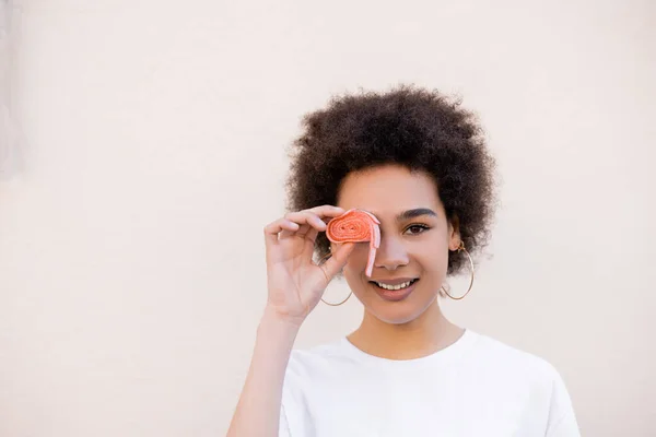 Pleased Young African American Woman Covering Eye Jelly Bubble Tape — Stockfoto