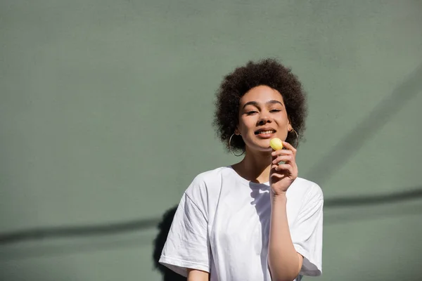 Pleased African American Woman Eating Yellow Candy — 스톡 사진