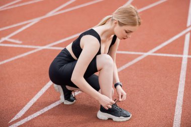 Siyah spor giyimli, spor ayakkabılı bir kadının stadyuma uzanan uzun görüntüsü.