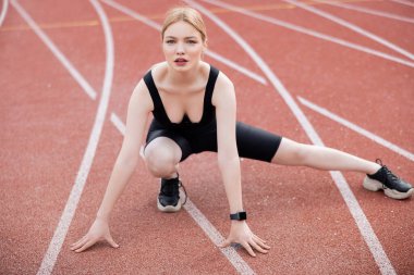 Siyah spor giysili bir kadının spor sahasında egzersiz yapması.