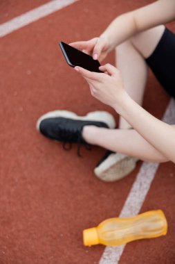 Beyaz ekran ile akıllı telefon tutan bulanık sporcu kadın görüntüsü
