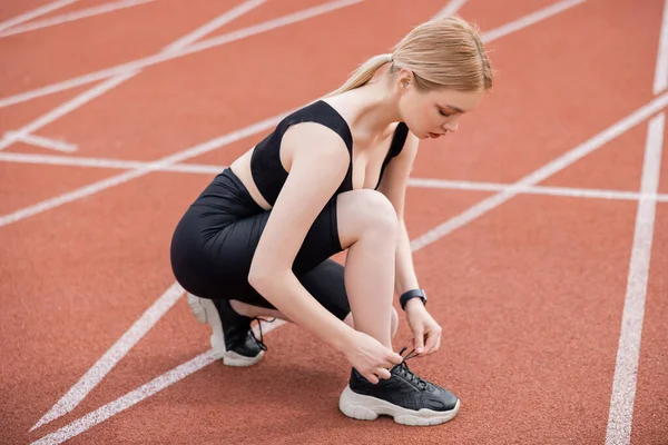 Siyah spor giyimli, spor ayakkabılı bir kadının stadyuma uzanan uzun görüntüsü.