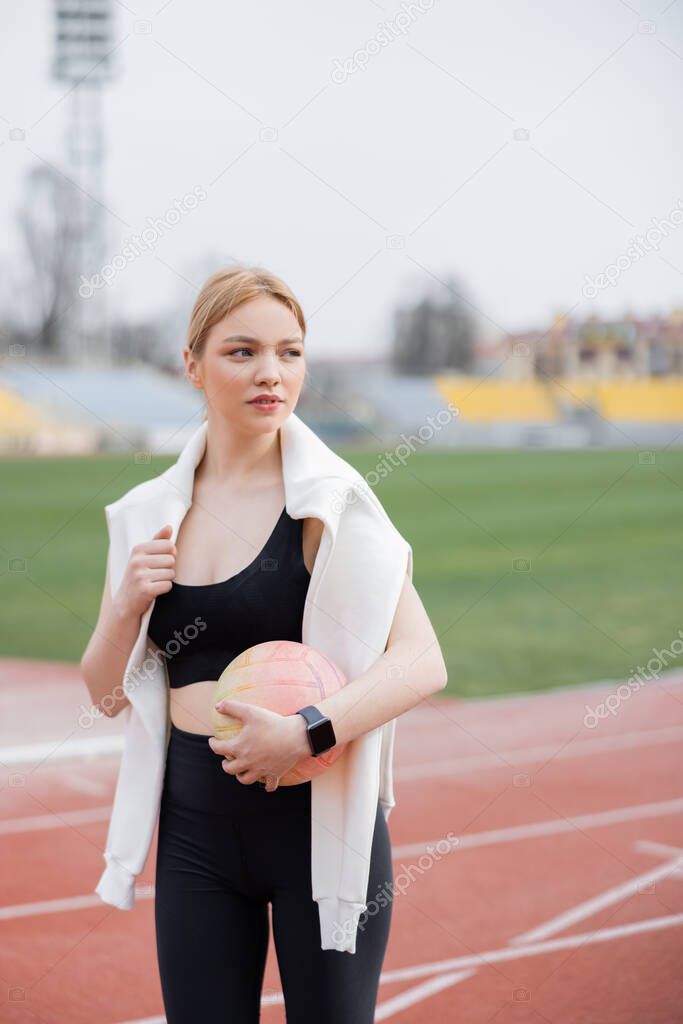 sportswoman holding ball while looking away outdoors